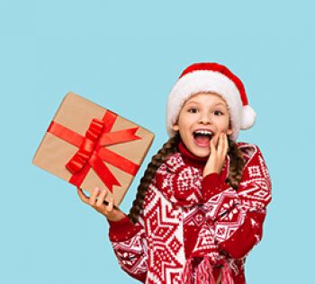 A girl smiling with a present while wearing winter clothes