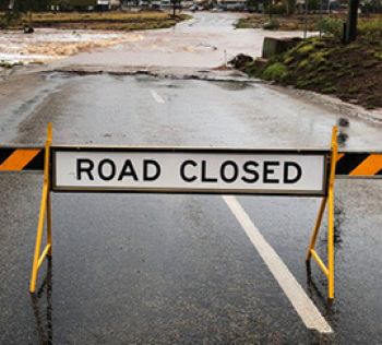 A road closed sign before a flooded part of road