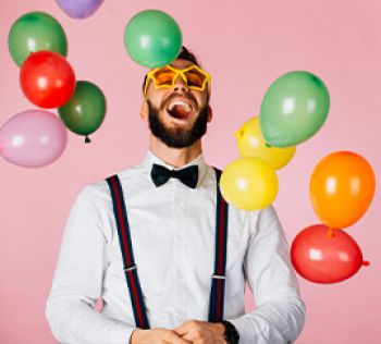 A man smiling surrounded by balloons