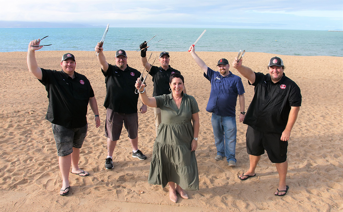 People holding barbecue tongs on The Strand beach