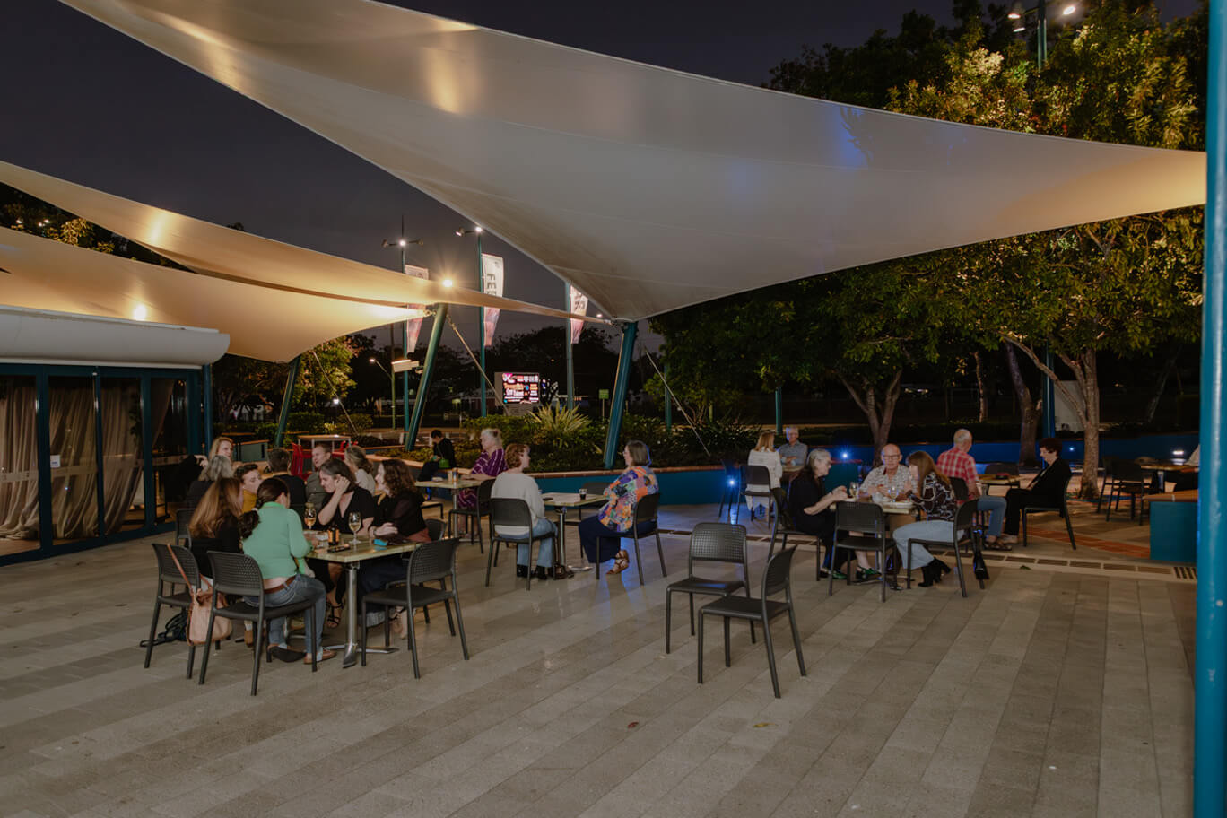 People sitting at tables out front of Townsville Civic Theatre