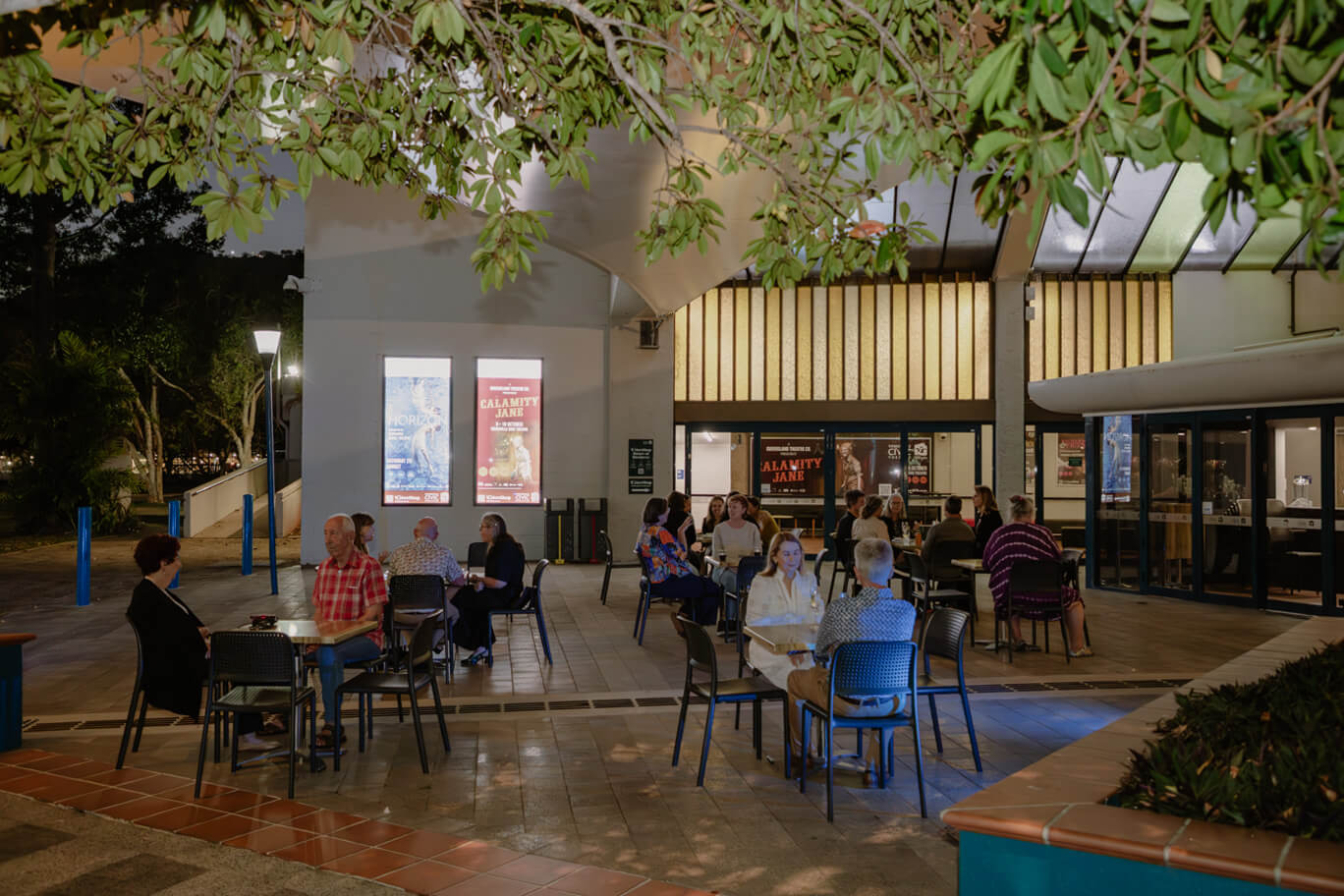 People sitting at tables out front of Townsville Civic Theatre
