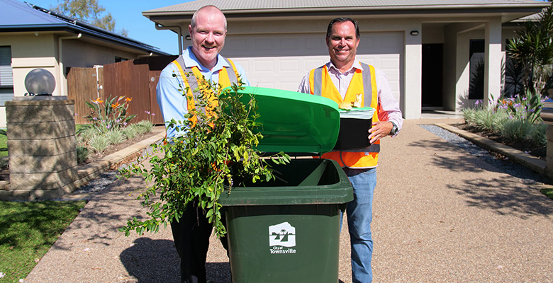Team Manager Waste Services Matt McCarthy and Townsville Water and Waste Committee Chairperson Russ Cook with the brand new lime green-lidded bin and the kitchen caddy being delivered to residents participating in the FOGO trial