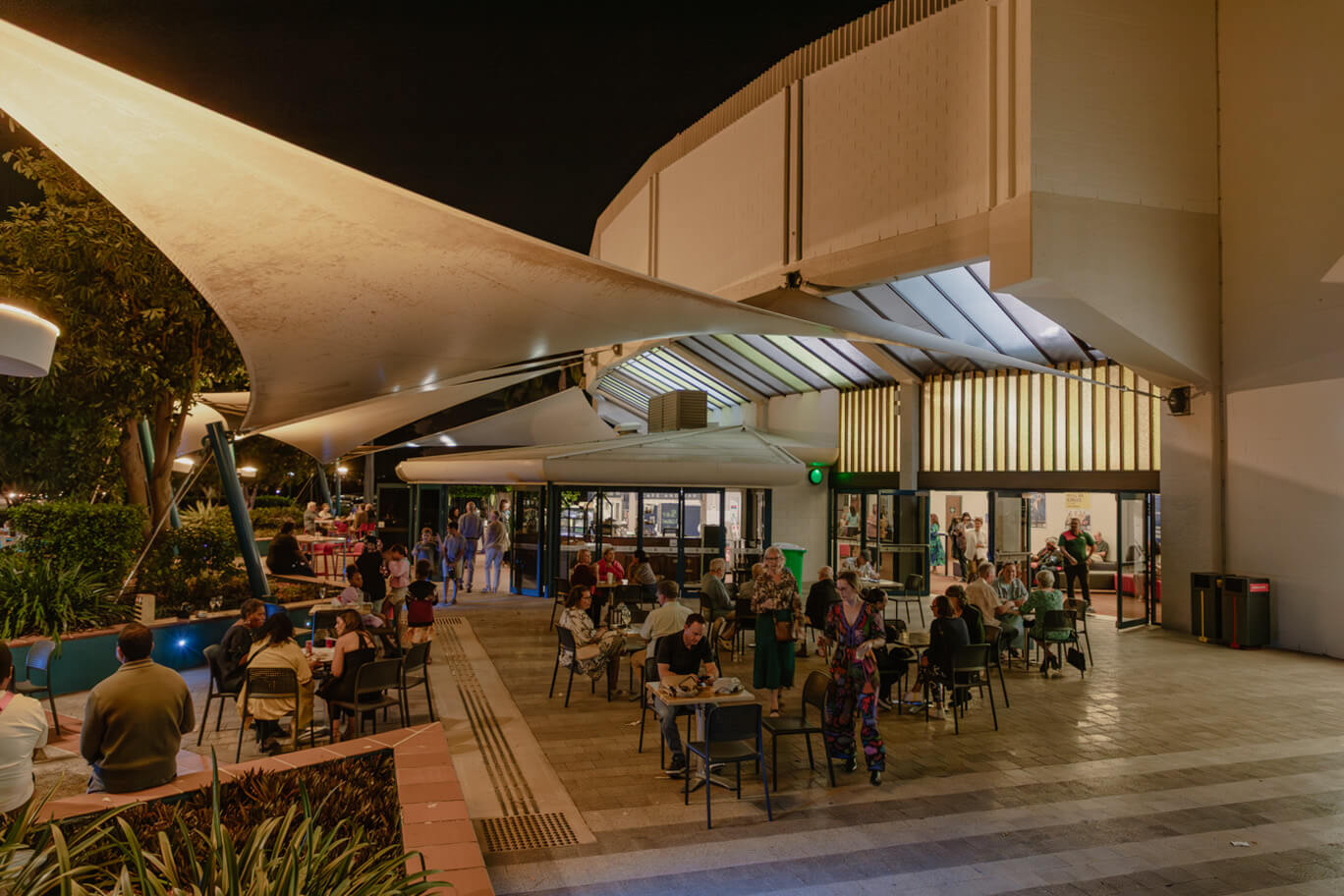 People sitting at tables out front of Townsville Civic Theatre
