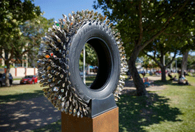 Karl De Waal, I've Been Everywhere Man, rubber tyre, souvenir spoons, plastic, steel, 200 x 100 x 40 cm Karl De Waal, I've Been Everywhere Man, rubber tyre, souvenir spoons, plastic, steel, 200 x 100 x 40 cm.