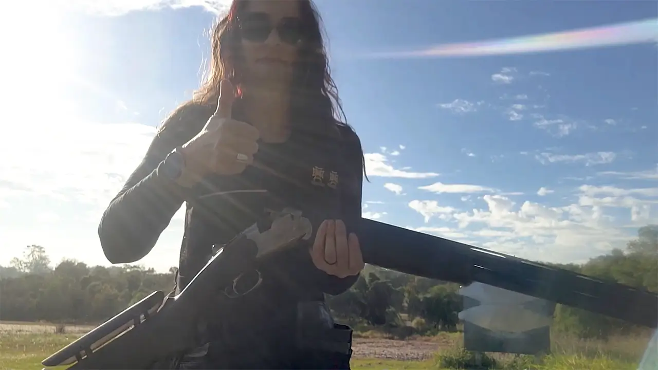 Rae Saheli holding a shotgun and doing a thumbs up