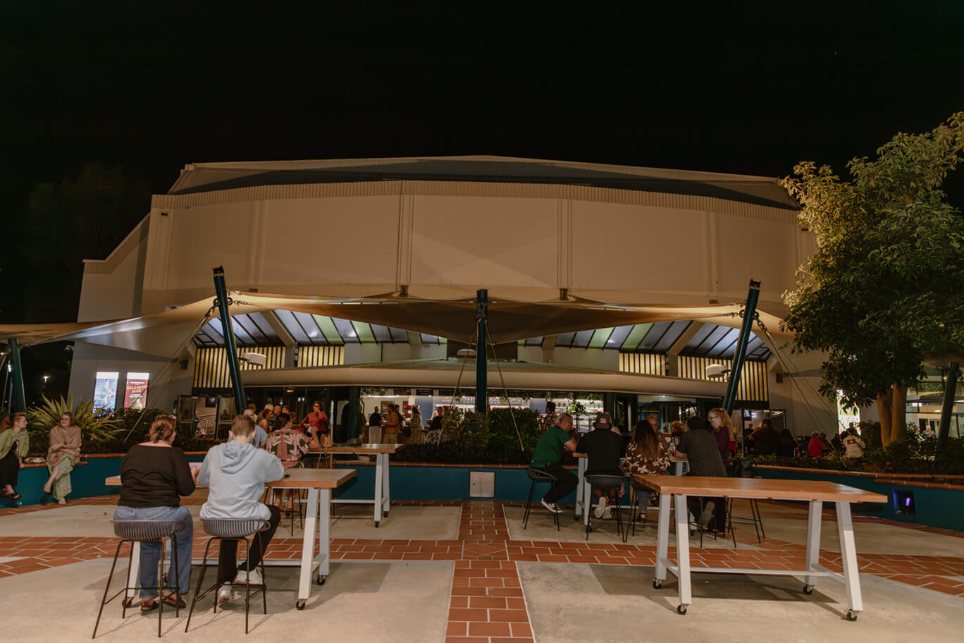 People sitting at tables out front of Townsville Civic Theatre