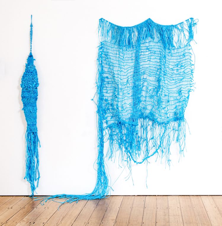 A blue net artwork against a white wall.