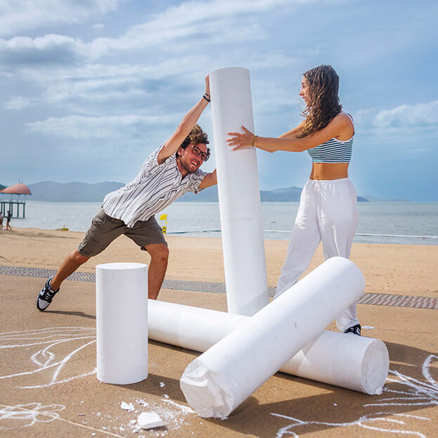 Man and woman posing with huge pieces of chalk
