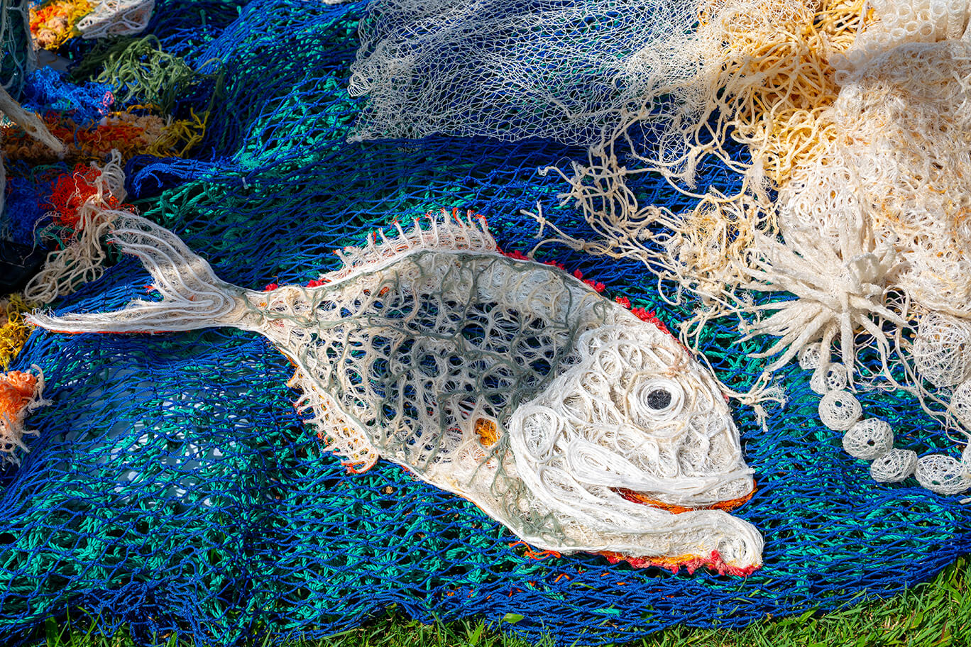 Anemones made of ghost net, beach found rope, sand, fabric, and fishing rod supports