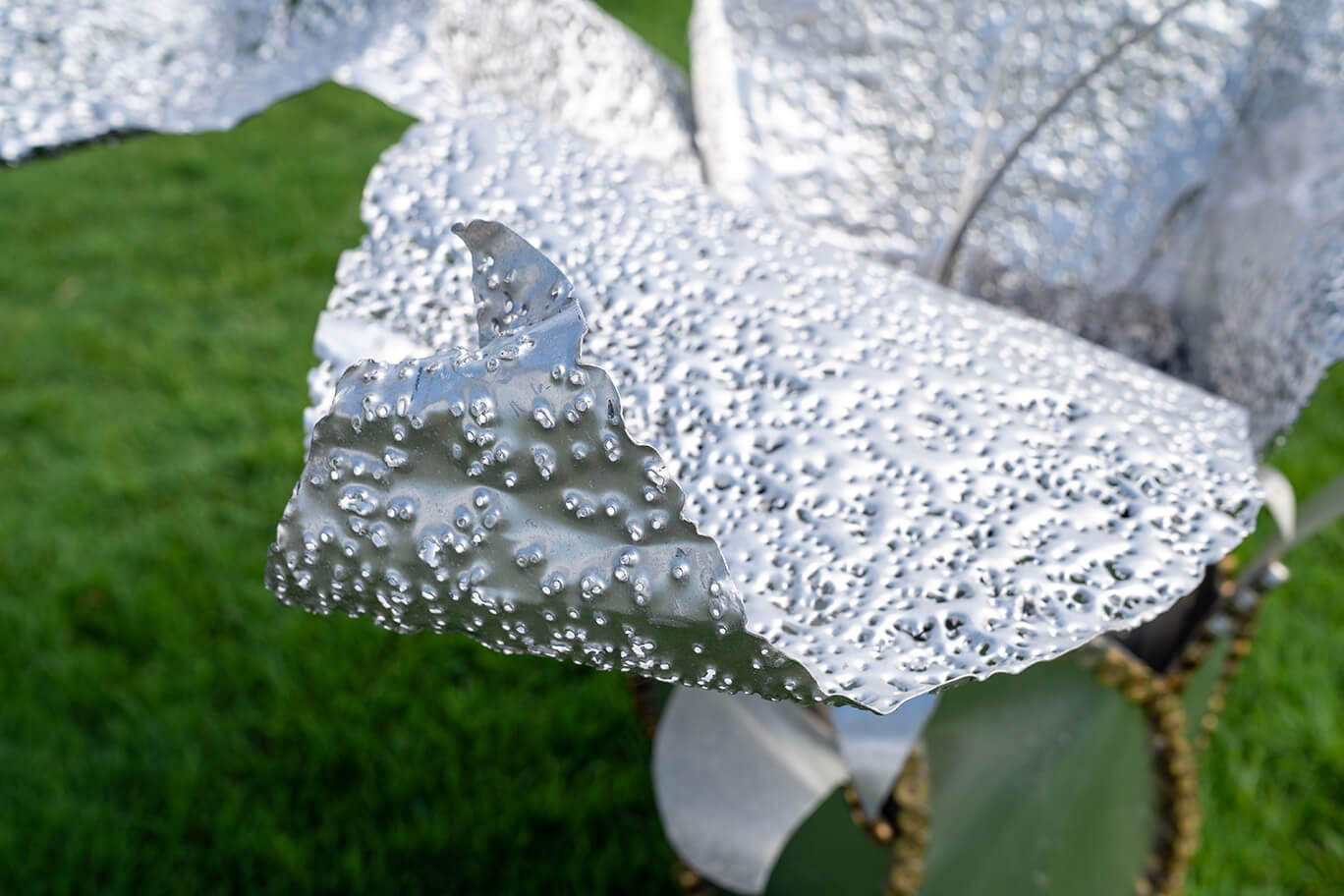 Three ethereal flowers created from recycled aluminium and copper, recycled shotgun shells, and brass casings