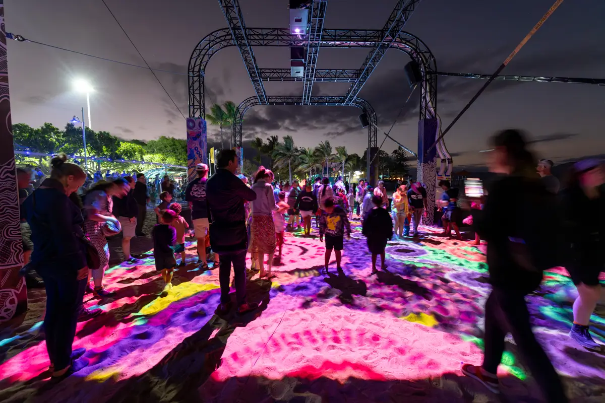 People standing on colourful artwork at night