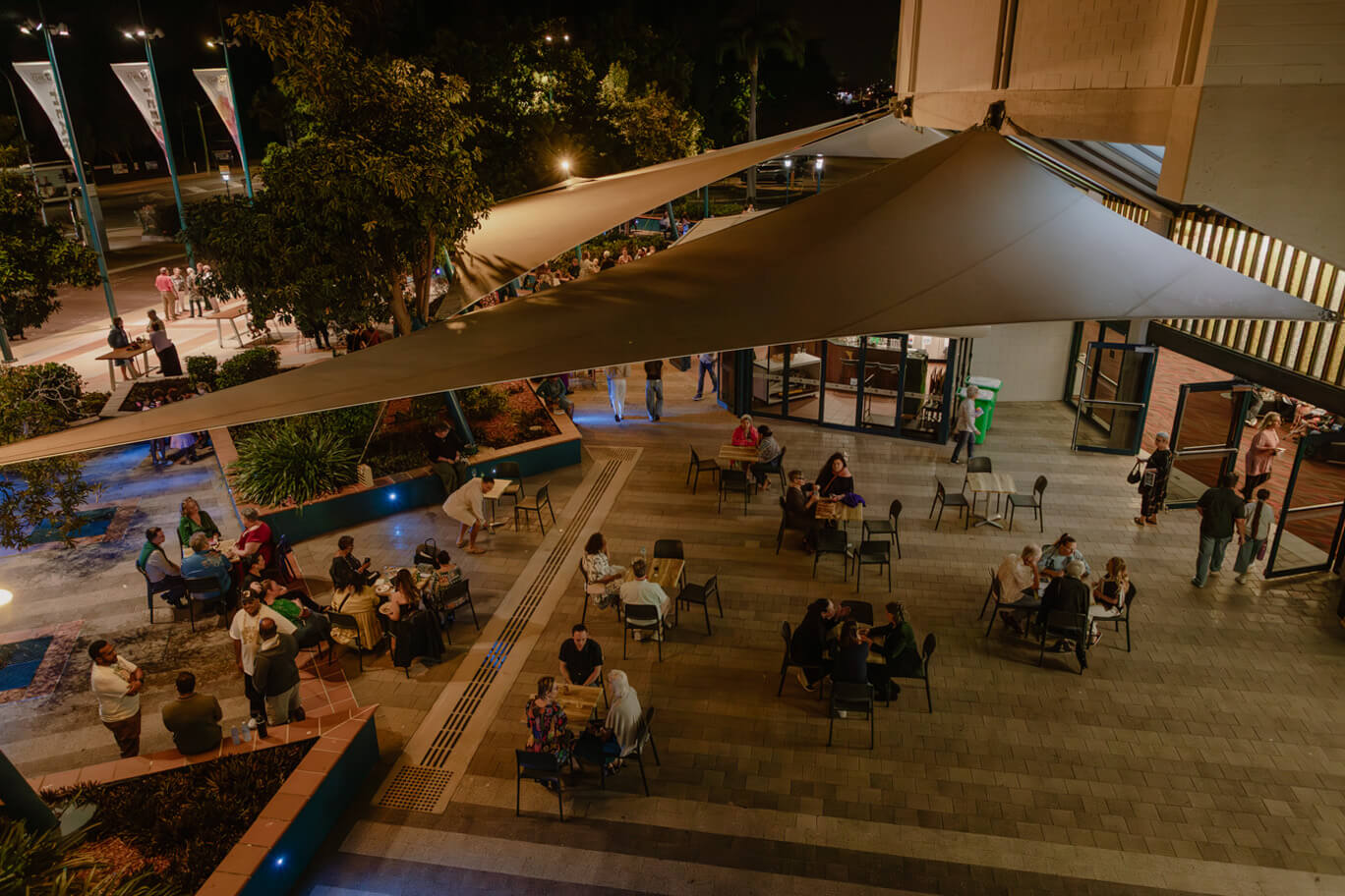 People sitting at tables out front of Townsville Civic Theatre