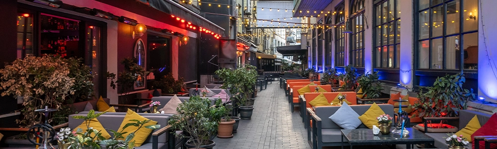 An inviting outdoor dining space in Tbilisi, Georgia with cozy lounges and string lights.