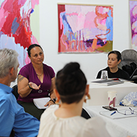 Transitions mentees presenting and discussing their works-in-progress at the group critique session at Umbrella, amidst artwork by Odessa Mahony-de Vries.