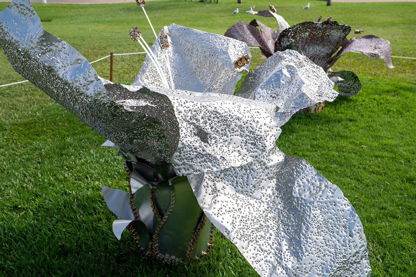 Three ethereal flowers created from recycled aluminium and copper, recycled shotgun shells, and brass casings