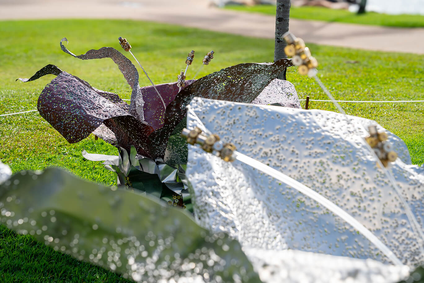 Three ethereal flowers created from recycled aluminium and copper, recycled shotgun shells, and brass casings
