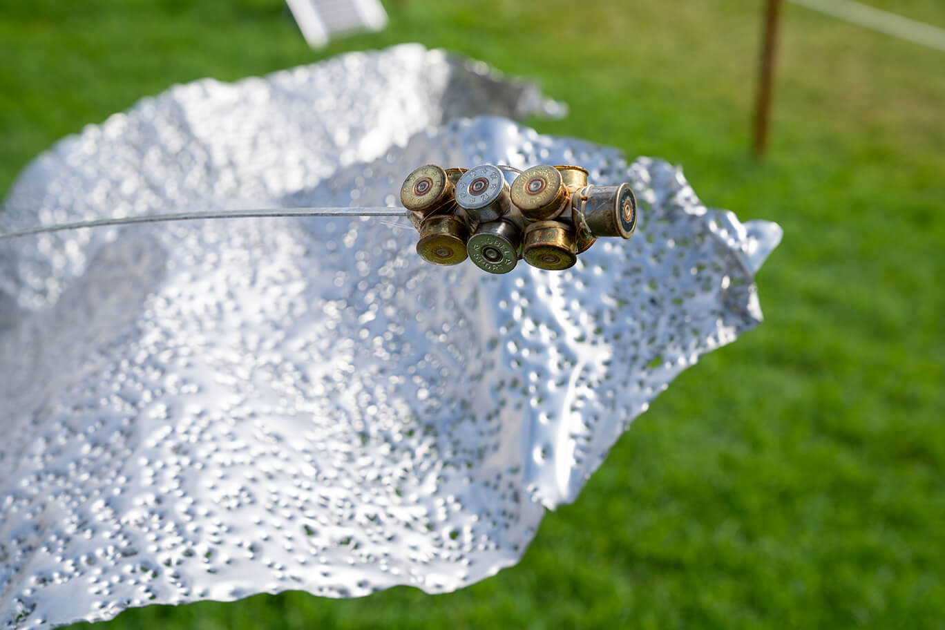 Three ethereal flowers created from recycled aluminium and copper, recycled shotgun shells, and brass casings